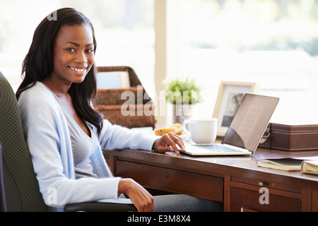 Donna che utilizza laptop sulla scrivania a casa Foto Stock