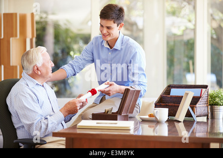 Nonno che mostra documento al nipote adolescente Foto Stock