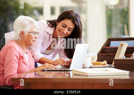 Figlia adulta aiutando la madre con il computer portatile Foto Stock