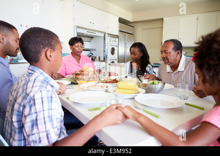 Famiglia Multi-Generation dicendo la preghiera prima di mangiare pasti Foto Stock
