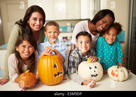 Le madri e i bambini rendendo lanterne di Halloween Foto Stock