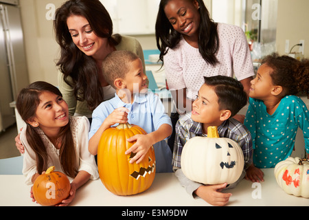 Le madri e i bambini rendendo lanterne di Halloween Foto Stock