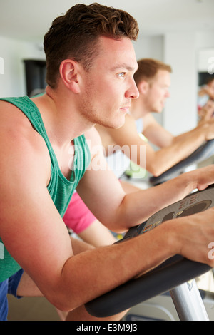 Due giovani uomini la formazione in palestra sulle macchine in bicicletta insieme Foto Stock