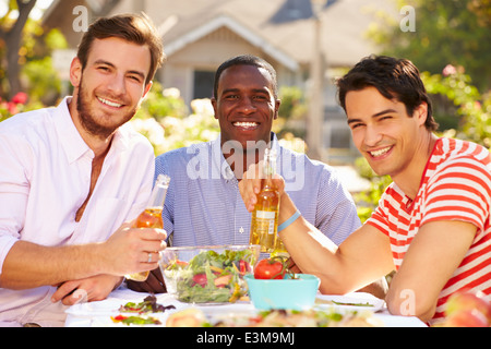 Tre amici maschi godendo di pasto al party all'aperto Foto Stock