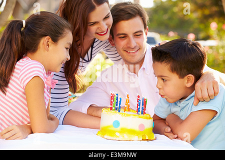 Famiglia festeggia il compleanno all'aperto con torta Foto Stock