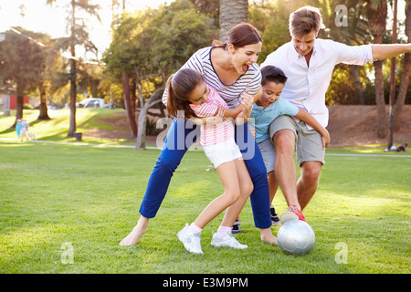 La famiglia che giocano a calcio nel parco insieme Foto Stock