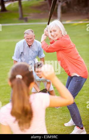 Nonni a giocare a baseball con i nipoti in posizione di parcheggio Foto Stock