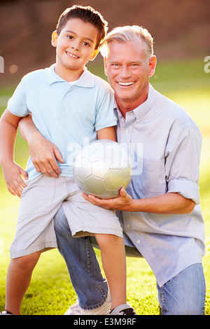 Nonno a giocare a calcio con il nipote in posizione di parcheggio Foto Stock