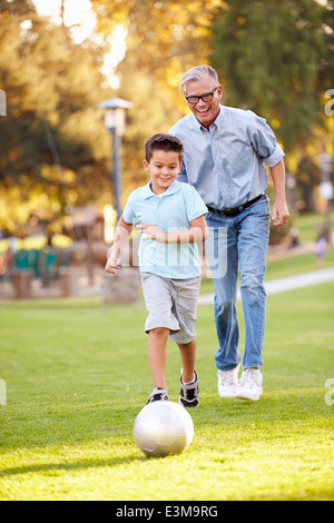 Nonno a giocare a calcio con il nipote in posizione di parcheggio Foto Stock