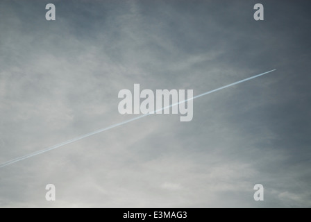 White contrail da un piano in un cielo nuvoloso Foto Stock