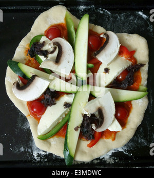 La pizza fatta in casa con salame e verdura prima della cottura, Londra Foto Stock