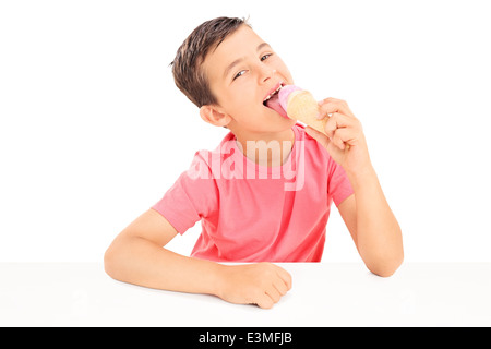 Gioiosa ragazzino di mangiare un gelato seduti a un tavolo Foto Stock