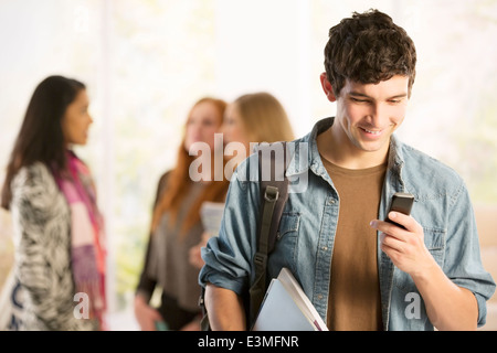 Studente di College per la messaggistica di testo con un telefono cellulare Foto Stock