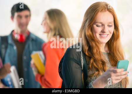 Studente di College per la messaggistica di testo con un telefono cellulare Foto Stock