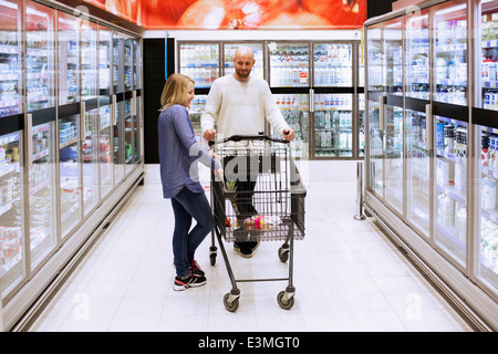 Lunghezza completa di padre e figlia con carrello nel corridoio del supermercato Foto Stock