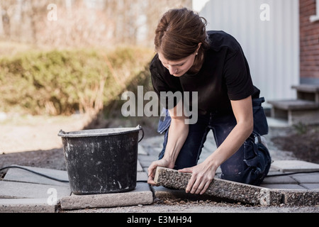 Falegname femmina il posizionamento di mattonelle in pietra in cantiere Foto Stock
