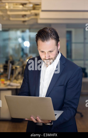 Metà adulto uomo d affari con computer portatile in ufficio Foto Stock