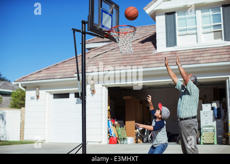 Nonno e nipote giocare a basket in viale di accesso Foto Stock