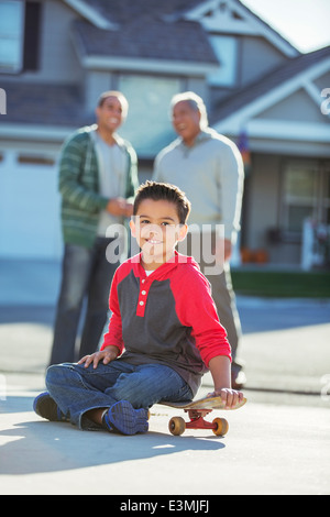 Ritratto di ragazzo sorridente su skateboard in viale di accesso Foto Stock