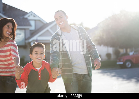 La famiglia felice in esecuzione su strada soleggiata Foto Stock