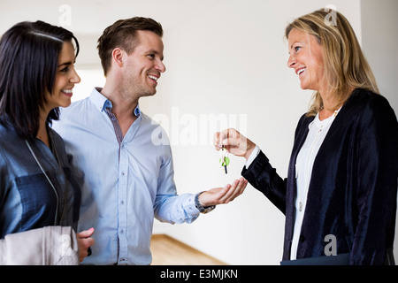 Felice agente immobiliare che dà le chiavi per accoppiarsi nella nuova casa Foto Stock