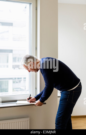 Vista laterale di imprenditore iscritto al davanzale a casa Foto Stock