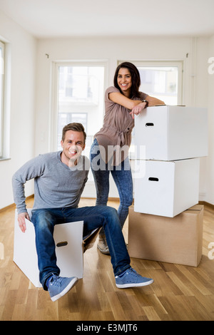 Lunghezza completa di felice metà adulto giovane con contenitori per il trasloco a casa Foto Stock