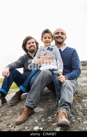 Ritratto di felice maschio famiglia omosessuale rilassante su roccia Foto Stock