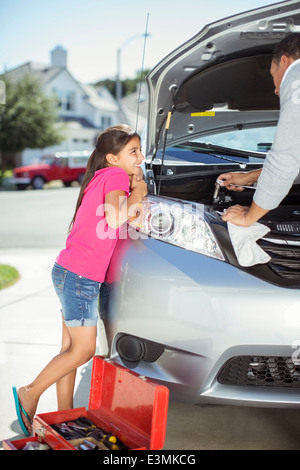 Figlia che guarda il padre fix auto motore Foto Stock