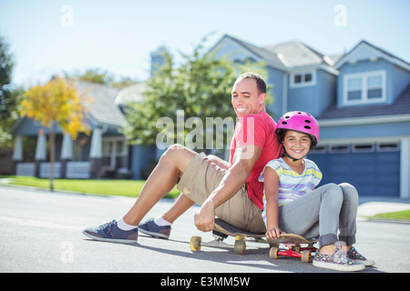 Padre e figlia seduti su skateboard Foto Stock