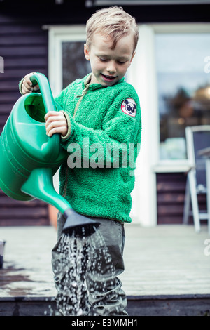 Boy utilizzando annaffiatoio in cantiere Foto Stock