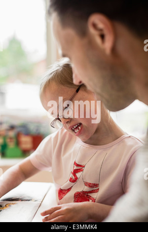 La ragazza con la sindrome di down di studiare da padre a casa Foto Stock