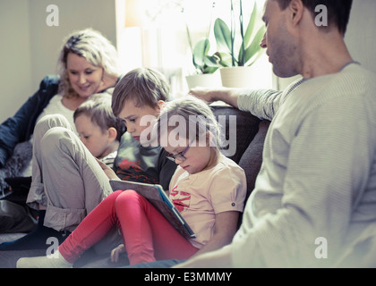 Famiglia di cinque seduti sul divano di casa Foto Stock