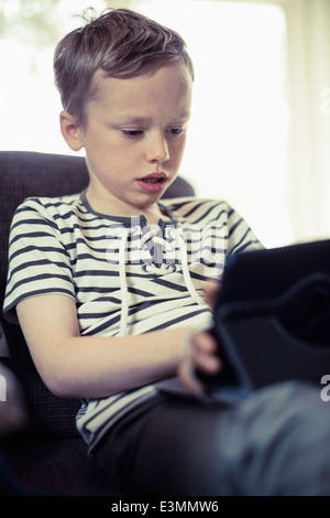 Ragazzo con tavoletta digitale sul divano Foto Stock