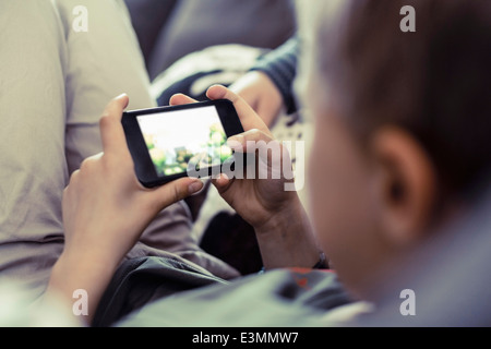 Ragazzo giocando su telefono cellulare a casa Foto Stock