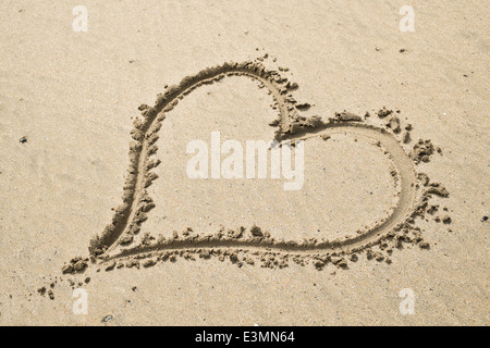 Un cuore disegnato nella sabbia su una soleggiata spiaggia sabbiosa Foto Stock