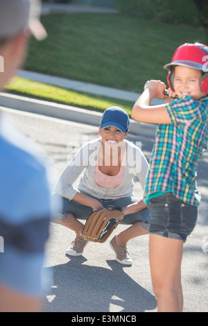 La famiglia a giocare a baseball in strada Foto Stock