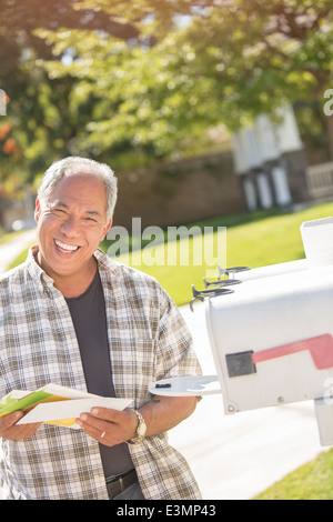 Ritratto di uomo sorridente recupero posta dalla mailbox Foto Stock