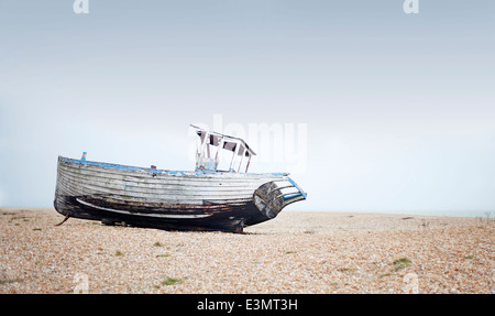 Elica in legno vecchie barche da pesca a sinistra sulla spiaggia a decadimento su una deserta spiaggia ghiaiosa Foto Stock