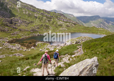 Camminatori sul sentiero da Bwlch Tryfan a Llyn Bochlwyd e Y Gribin in estate in montagna Snowdonia National Park Galles del Nord Gran Bretagna Foto Stock