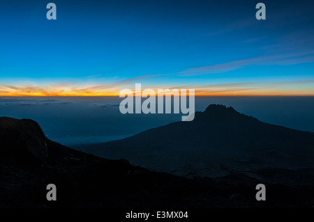 La mattina presto luce splende attraverso le nuvole dietro Mawenzi come ci avviciniamo a Stella punto sul Kilimanjaro Foto Stock