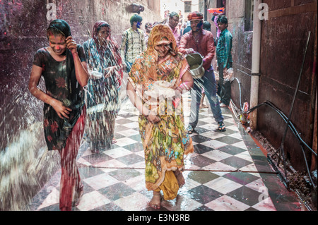 Donne imbevuto di acqua colorata durante le celebrazioni di holi festival, Vrindavan, India Foto Stock