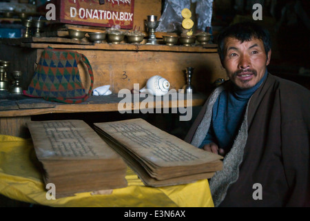 Un tibetano monaco buddista legge testi sacri nel villaggio di SAMDO sul intorno il MANASLU TREK - REGIONE NUPRI, NEPAL Foto Stock