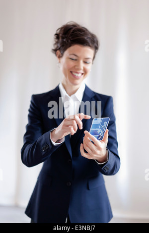 Felice imprenditrice utilizzando lo smartphone trasparente Foto Stock