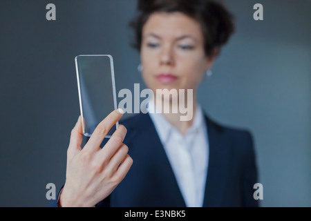 Fiducioso imprenditrice tenendo lo smartphone trasparente su sfondo colorato Foto Stock