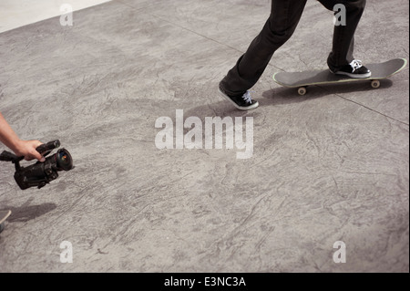 Immagine ritagliata dell'uomo video riprese amico lo skateboard in posizione di parcheggio Foto Stock