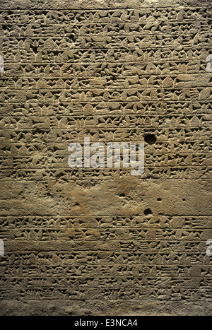 Re della stele con iscrizione e un rilievo raffigurante il re Sennacherib pregando davanti del divino i simboli. Calcare. Foto Stock