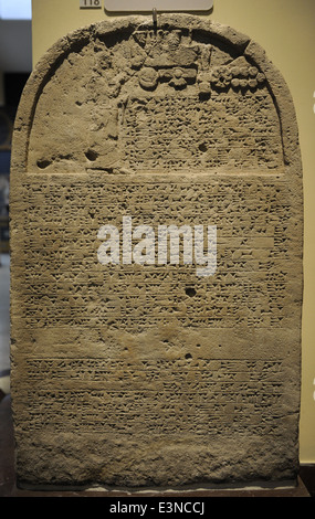 Re della stele con iscrizione e un rilievo raffigurante il re Sennacherib pregando davanti del divino i simboli. Calcare. Foto Stock