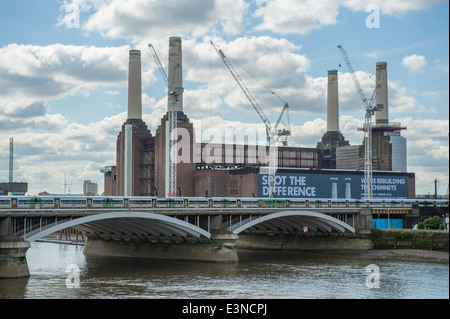 Iconica Battersea Power Station edificio in fase di riconversione, con un treno che attraversa il ponte Cremorne Foto Stock