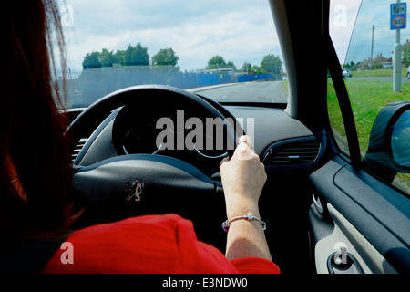 Una femmina di guida di una vettura che mostra la sua mano destra sul volante England Regno Unito Foto Stock